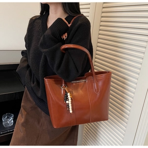 Dettaglio della grande borsa tote marrone vintage in ecopelle lucida con perline decorative