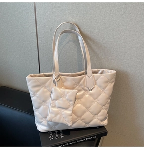 Detailed close-up of quilted cream tote bag with floral embroidery and mini coin purse