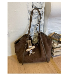 Detailed view of dark brown suede tote bag with adjustable straps and cute rabbit charm