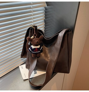 Détail du sac seau marron foncé avec un joli charm d'ours en peluche comme accessoire