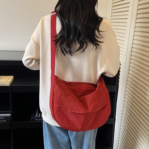 Detail of red nylon crescent crossbody bag with adjustable strap worn by model