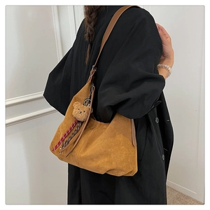 Detailed side view of brown suede tote bag with cute plush bear charm on a model