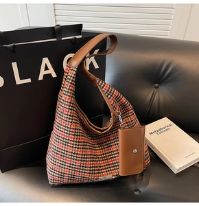 Detail of vintage houndstooth fabric texture and brown leather strap on a tote bag