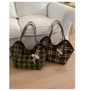 Detail view of plaid fabric tote bags with plush rabbit charms on a cozy home sofa