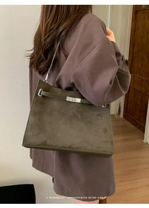 Detail view of olive green suede tote bag with silver metal twist lock and straps