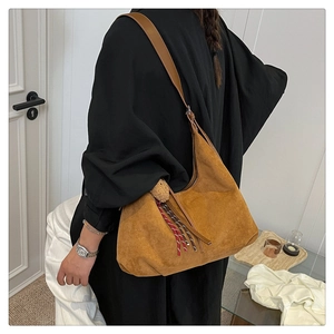 Detail view of caramel suede hobo bag with colorful woven rope tassel and wide strap