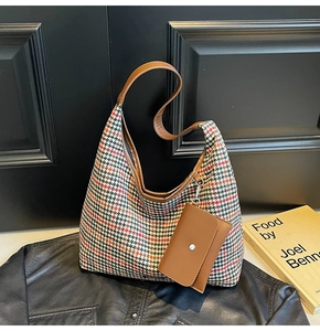 Close-up of hobo bag featuring green and red houndstooth weave and leather strap