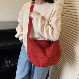 Large red nylon crescent crossbody bag shown worn by a model for scale and capacity