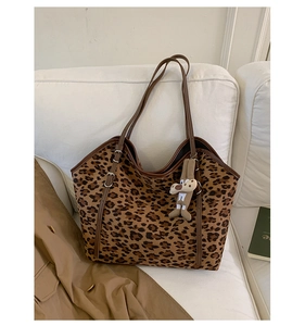 Detail of leopard print tote bag featuring a cute plush bunny pendant on leather handle
