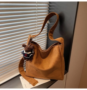 Détail d'un sac cabas en similicuir marron avec pendentif ours et large bandoulière