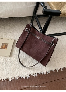 Detailed view of the dark brown suede tote bag with silver turn-lock and leather straps