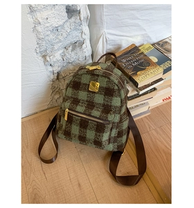 Detail of green and brown plaid wool mini backpack with golden metal logo and zipper