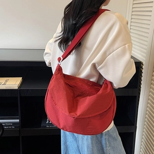 Detailed view of red pleated nylon crescent bag with wide shoulder strap and white buckle