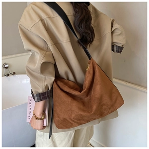Vue d'épaule d'un grand sac cabas en daim caramel avec bandoulière en cuir noir chic