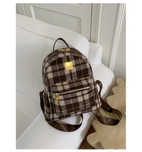 Detail of checkered plaid backpack with gold metal plaque and premium fleece texture