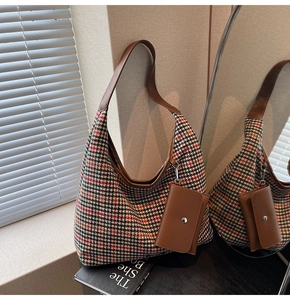 Detail of houndstooth tote bag featuring brown leather strap and small accessory pouch
