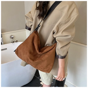 Detail of caramel suede hobo bag with black leather strap and gold metal buckle