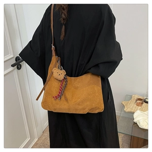 Macro shot of brown suede hobo bag detailing with adjustable strap and bear pendant