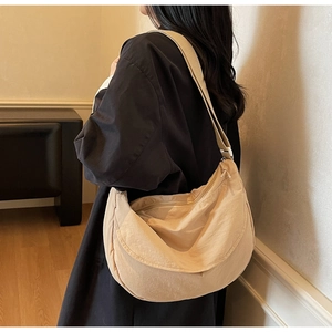 Detail of beige crescent nylon crossbody bag with adjustable wide shoulder strap on model