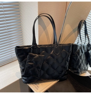 Detail view of black quilted tote bag with floral embroidery and small zipper pouch