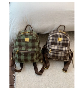 Detailed close-up of thick plaid wool fabric and golden metal buckle on backpack