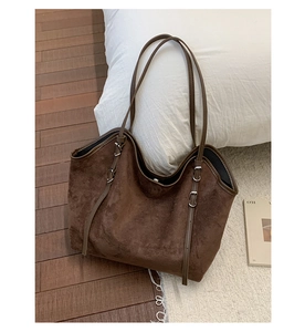Detail view of brown suede tote bag featuring metallic buckle and adjustable shoulder strap