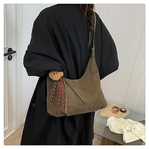 Detail view of large dark brown suede hobo bag with cute plush bear charm and woven cord
