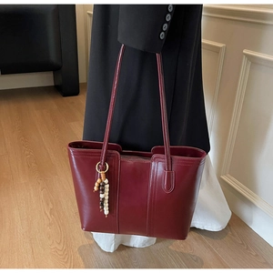 Dettaglio macro della borsa tote in pelle rosso vino con ciondoli di nappe di perline