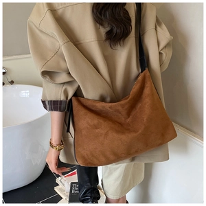 Vue détaillée d'un grand sac hobo en daim marron avec bandoulière noire et boucle dorée