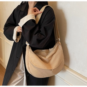 Close-up of large khaki crescent crossbody bag with wide strap on a model