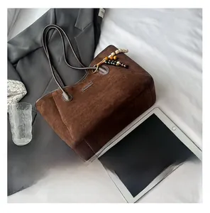 Detail of dark brown suede tote bag featuring a decorative wooden bead tassel accent