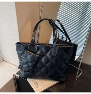 Detail of black quilted leather tote bag with embossed floral patterns in a cozy interior