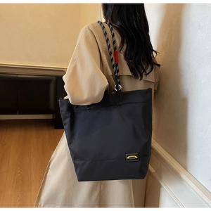 Detail of waterproof nylon tote bag with black and white braided rope handle on model