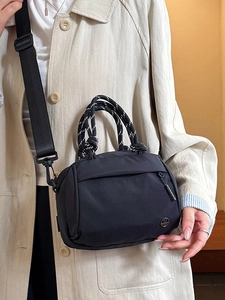 Minimalist black nylon crossbody bag with contrast striped handles and wide shoulder strap