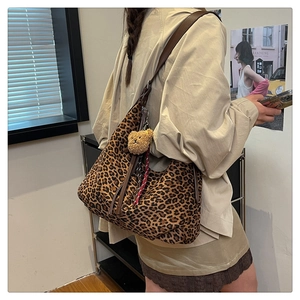 Detail shot of leopard print hobo bag with leather strap and cute plush bear charm accessory