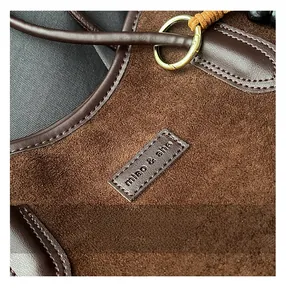 Detail of suede and brown leather shoulder bag with stitching and gold metal ring