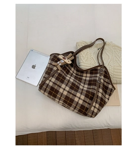 Flat lay of plaid tote bag with brown straps, cute bunny charm, and casual lifestyle props