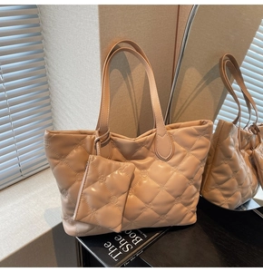 Detail of quilted beige tote bag set with floral embossing and polished faux leather texture