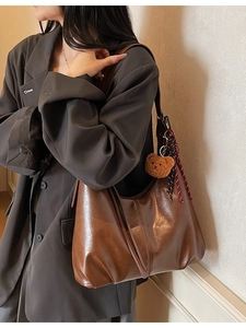 Vintage dark brown large tote shoulder bag with bear charm on a model in a grey suit