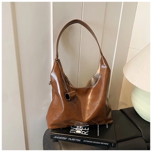Detail of a brown oil-wax leather tote bag with unique rolled leather trim and wide strap