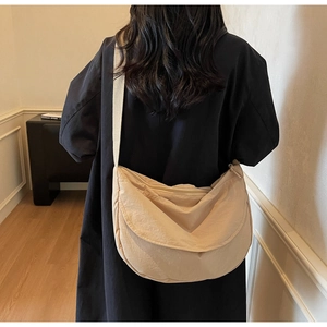 Detail of a large beige nylon crescent bag featuring a wide strap and zip closure