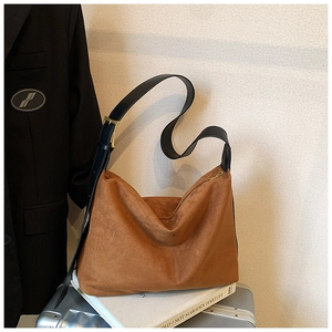 Détail du sac à bandoulière en daim marron foncé avec forme trapèze et sangle réglable