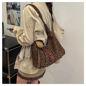 Detail view of leopard print hobo bag with wide brown strap and cute plush bear charm