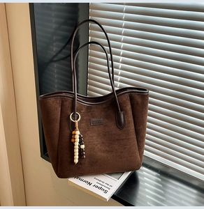 Detail of dark brown faux suede tote bag with leather handles and bohemian bead charm
