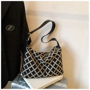Détail d'un sac bandoulière tricoté à carreaux noirs et blancs avec boucle dorée et cuir