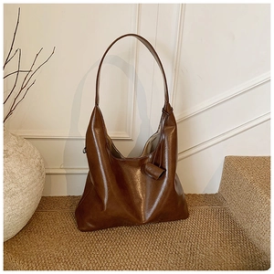 Detailed view of dark brown hobo shoulder bag with glossy faux leather on woven rug