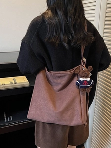 Sac seau en daim marron avec pendentif ours mignon présenté dans un décor lifestyle