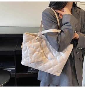 Detail view of beige quilted tote bag with mini pouch and floral stitching details