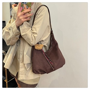 Detail view of brown faux suede tote bag featuring a cute plush bear charm and zipper side