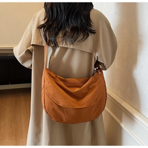 Close-up of bright orange nylon crescent crossbody bag with adjustable strap and textured fabric